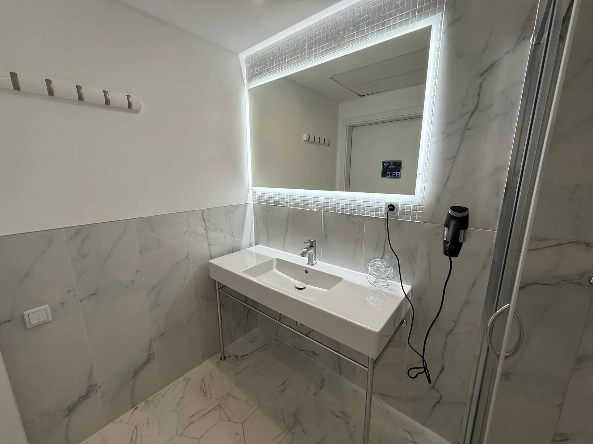 Marble bathroom with washbasin, illuminated mirror and shower