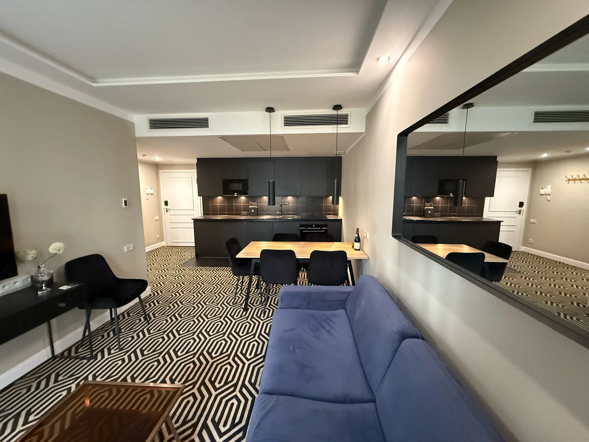 Open living, dining and kitchen area of the apartment with a blue sofa